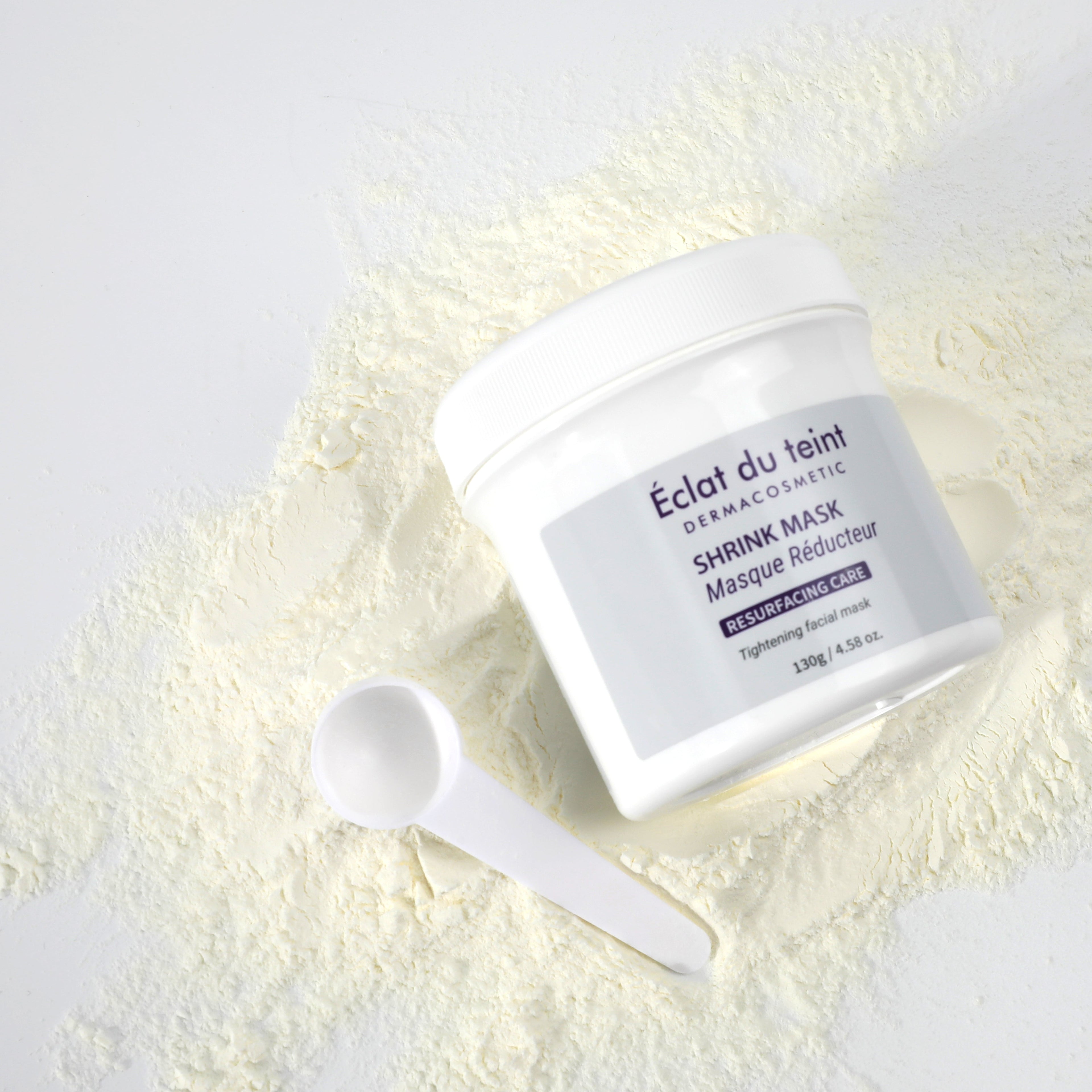 Shrink mask container with a spoon of shrink mask powder on a white background