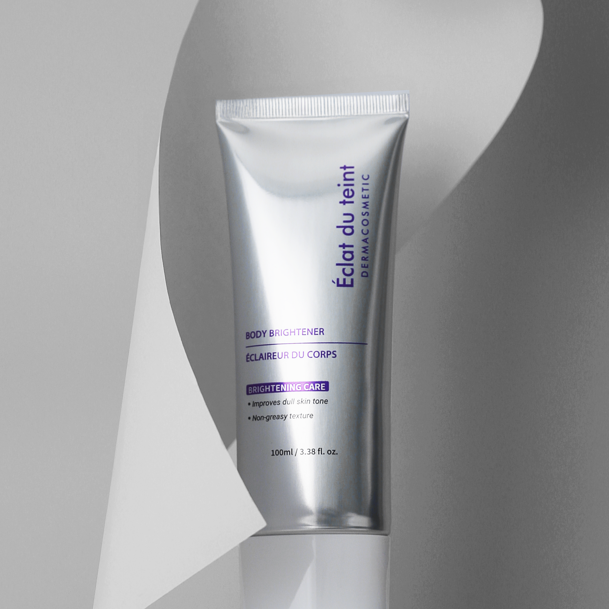 Tube of Éclat du Teint body brightener on a gray background